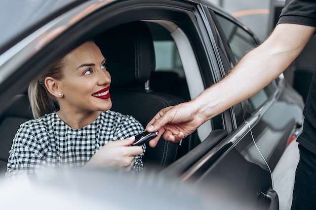En kvinna som tar emot nycklarna till sin bil hon köpt med ett billån.